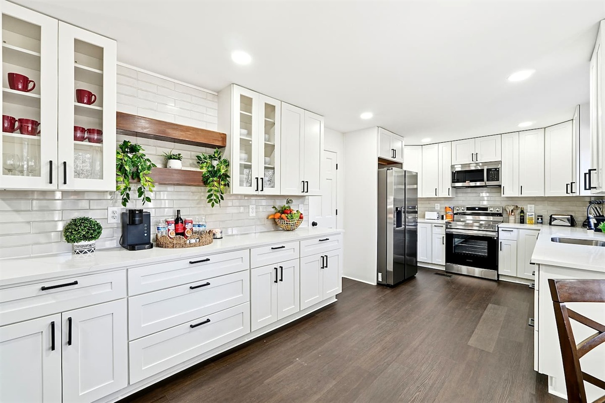 Bright white kitchen with a sleek, extended layout and ample counter space. The long layout offers plenty of countertop space, perfect for cooking, prepping, and everyday meals. Fully stocked with everything you need for a comfortable stay!
