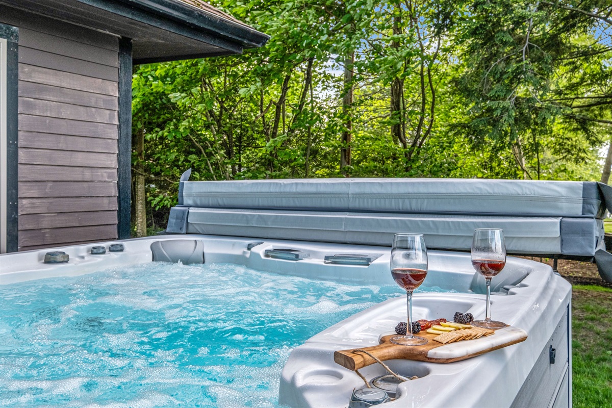 Hot tub with seating for 8 with its own tv, overlooking Lake Winnipesuakee and the mountain range in the distance