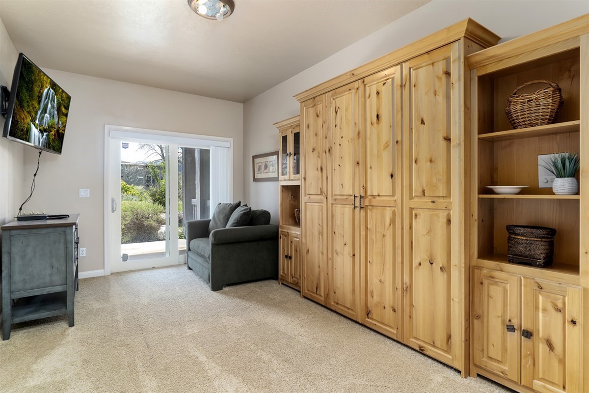 Versatile bedroom featuring a Murphy bed, seating area, and access to the outdoors.
