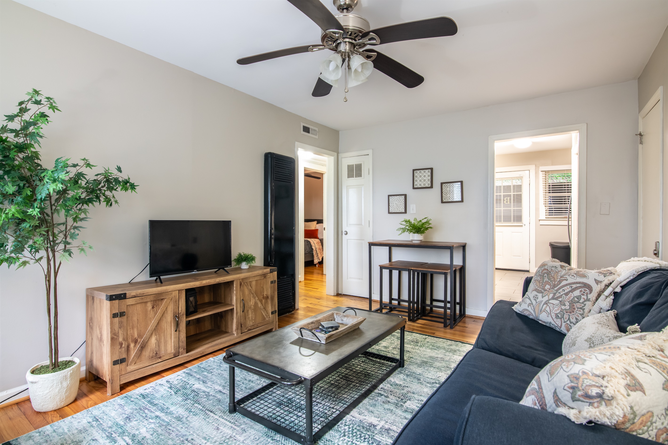 Spacious open-concept living area with modern furniture, entertainment setup, and a ceiling fan for added comfort.