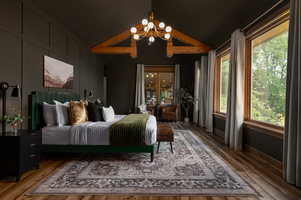 {Master Bedroom} Wake up surrounded by forest views in this spacious king suite with soaring wood beams, moody designer finishes, and a private ensuite bath.
