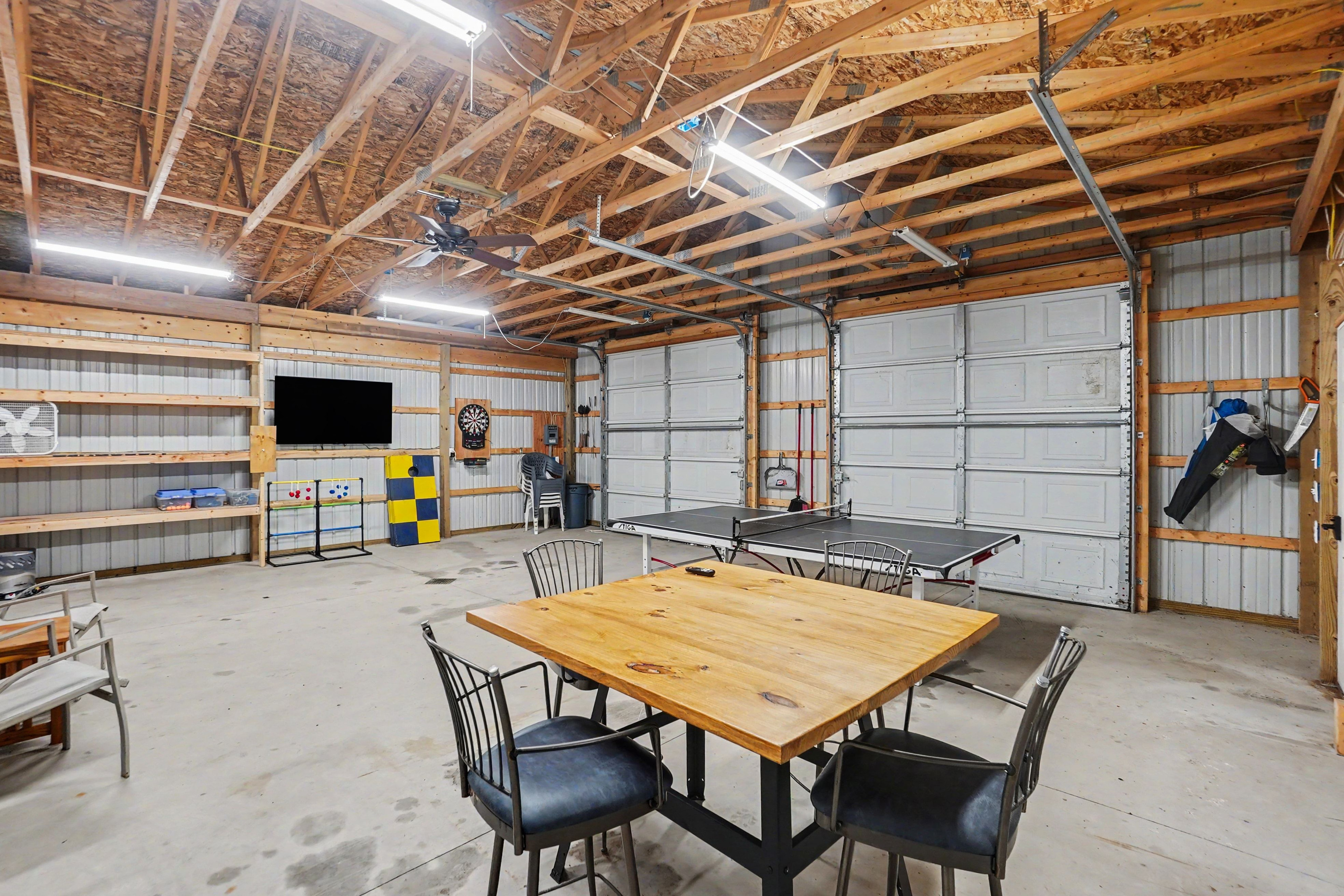 Game room with ping pong table, darts, tv and table and chairs.
