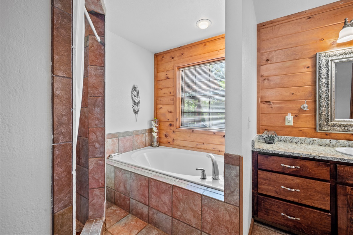 Bathtub, granite vanity, and big windows make this space feel warm and inviting.