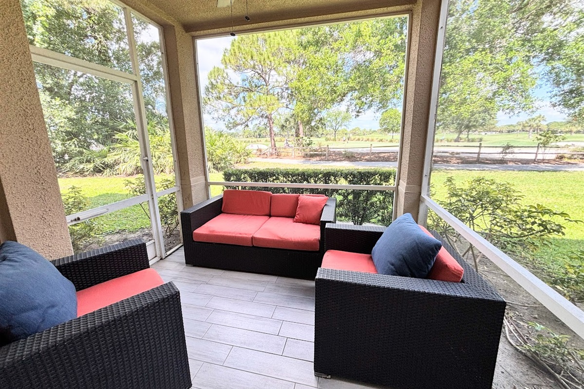 Private screened patio with comfortable outdoor seating and relaxing views of the surrounding green space.