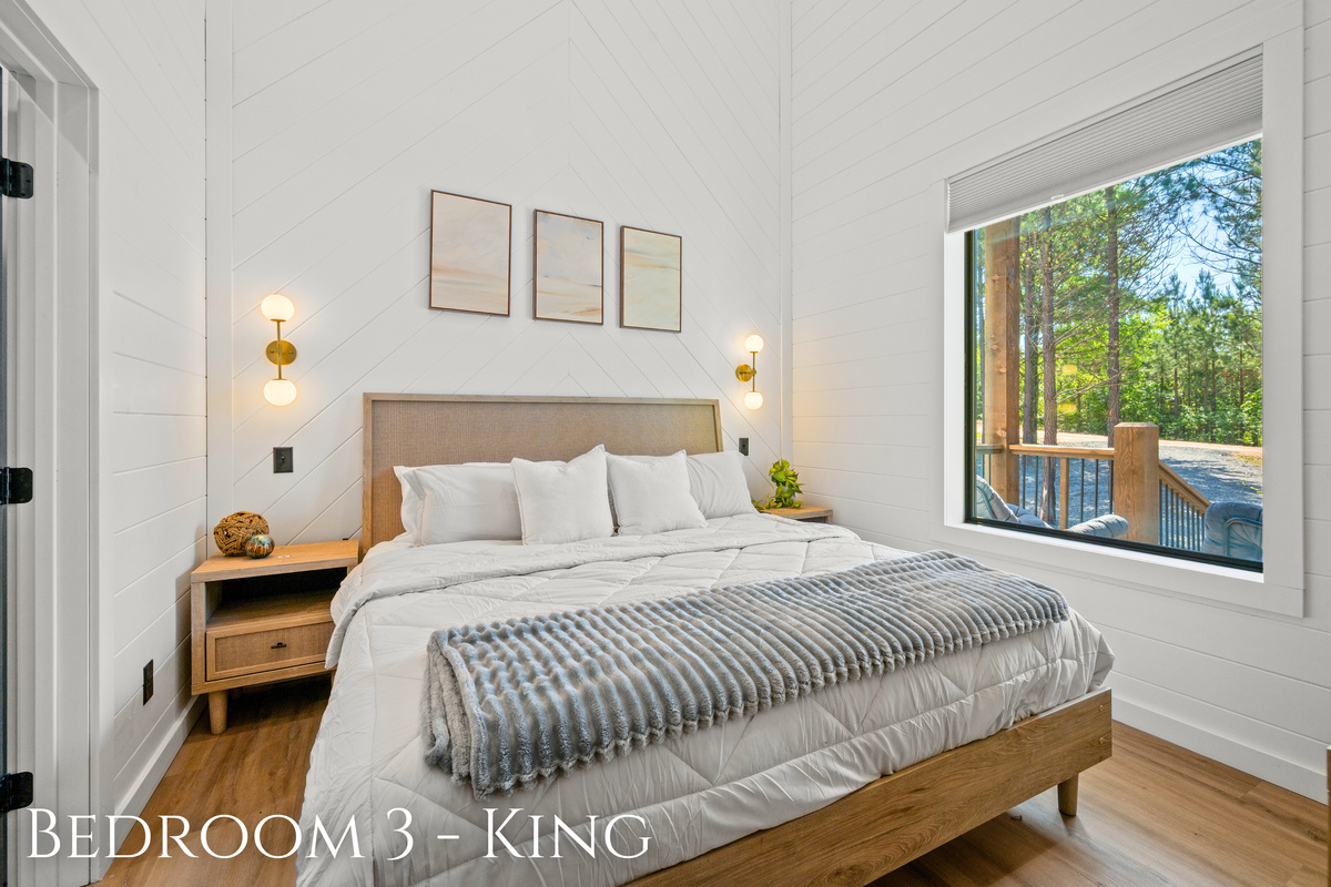 Soft neutral tones, natural light, and peaceful wooded views help this king bedroom feel bright, cozy, and ideal for restful mornings and quiet evenings.