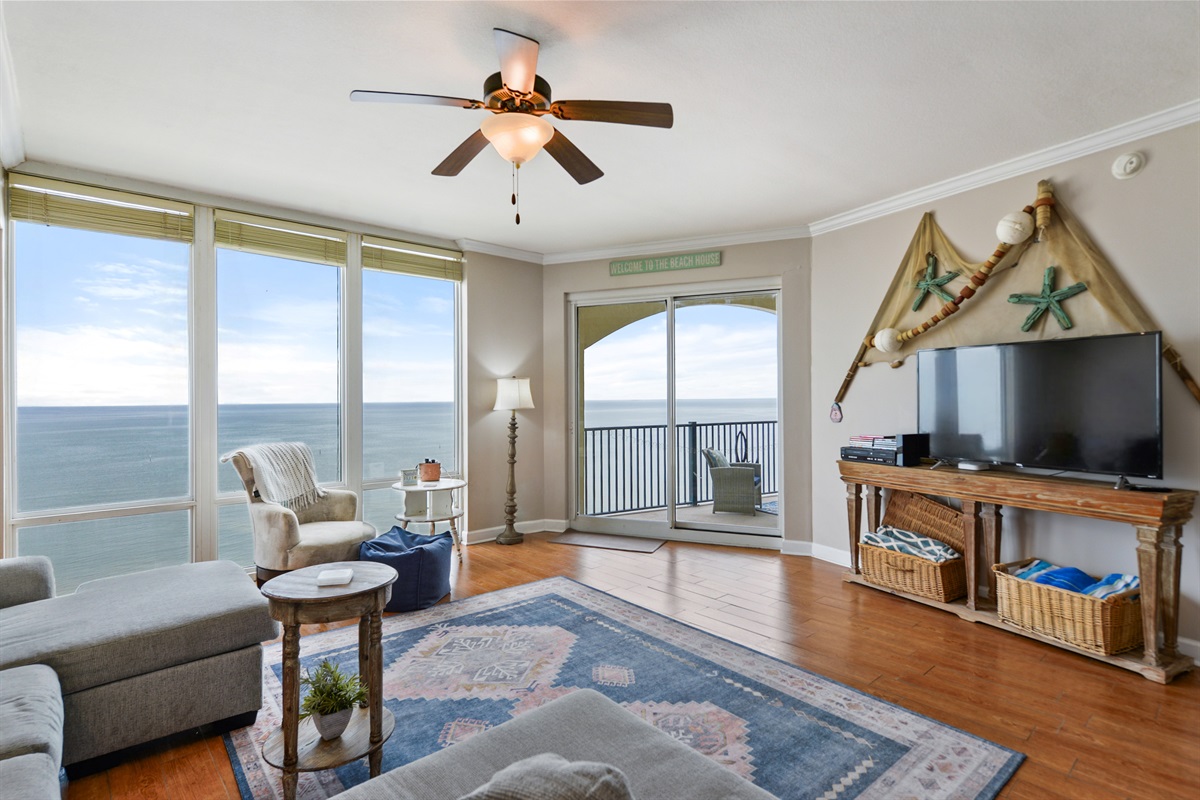 Living room with floor to window views, balcony access, big screen, huge sectional sofa.