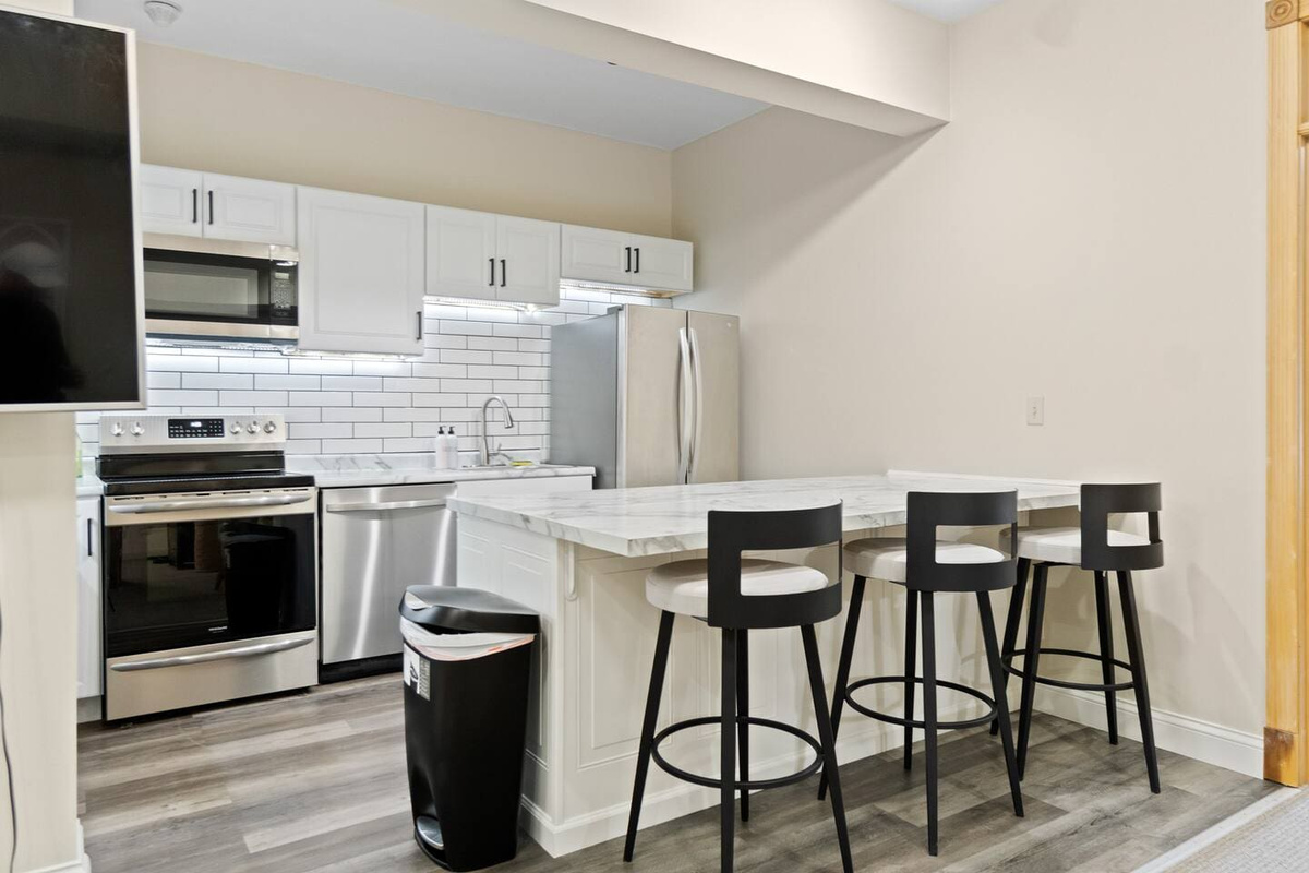 Modern kitchen featuring a sleek countertop with seating for three, complemented by elegant white interiors for a clean and stylish look.