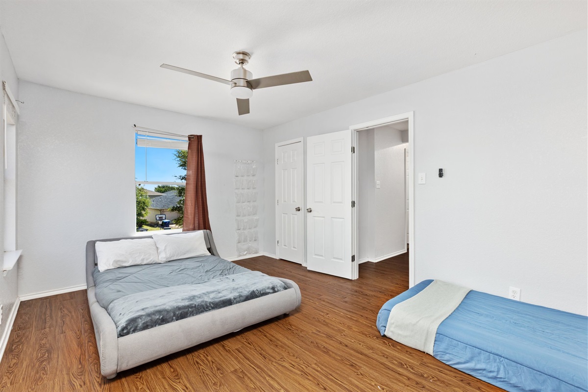 Bright queen and twin bedroom with ceiling fan, natural light, clothing storage, and premium linens. Extra pillows and blankets included.  Current decorative blankets, bedding, and wall art are not shown in these photos.