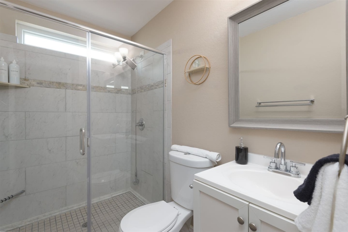 Guest bathroom with walk-in shower, glass doors, fresh towels, and a clean, practical setup for daily routines.