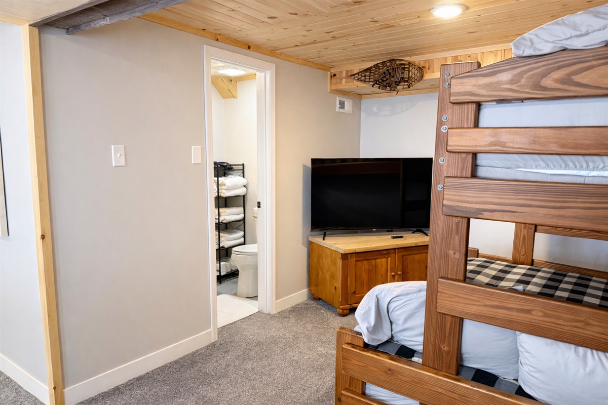 The basement bunk area, conveniently located next to the bathroom and TV. It's a great spot to relax, have some fun, and rest up after a day of adventures.