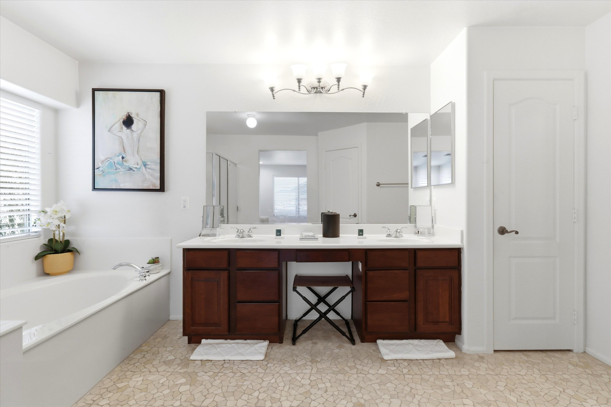 Bathroom with double sinks, a makeup vanity, soaking tub, and plenty of storage for getting ready.