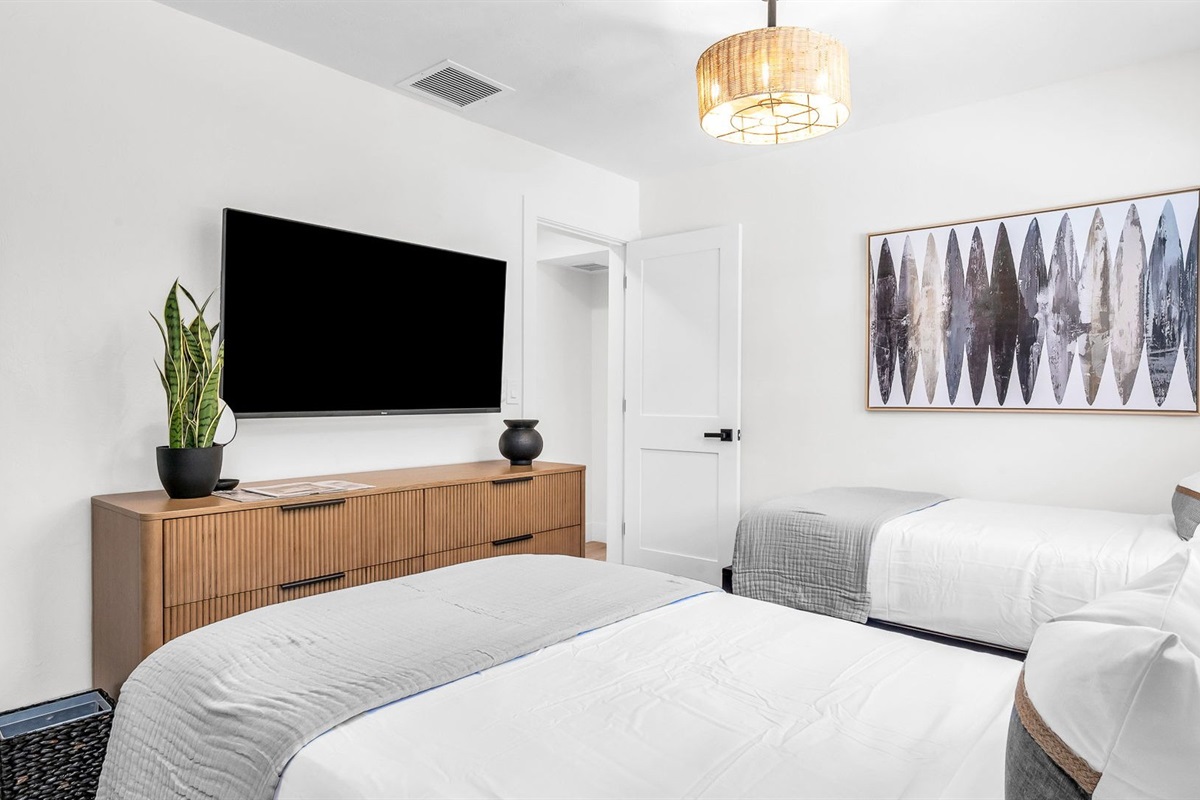 This light-filled twin bedroom combines comfort and style with coastal surf accents, two cozy twin beds, and premium linens. Guests will love the ROKU TV for entertainment and the abundant storage space, all ideally situated across from the guest bath.