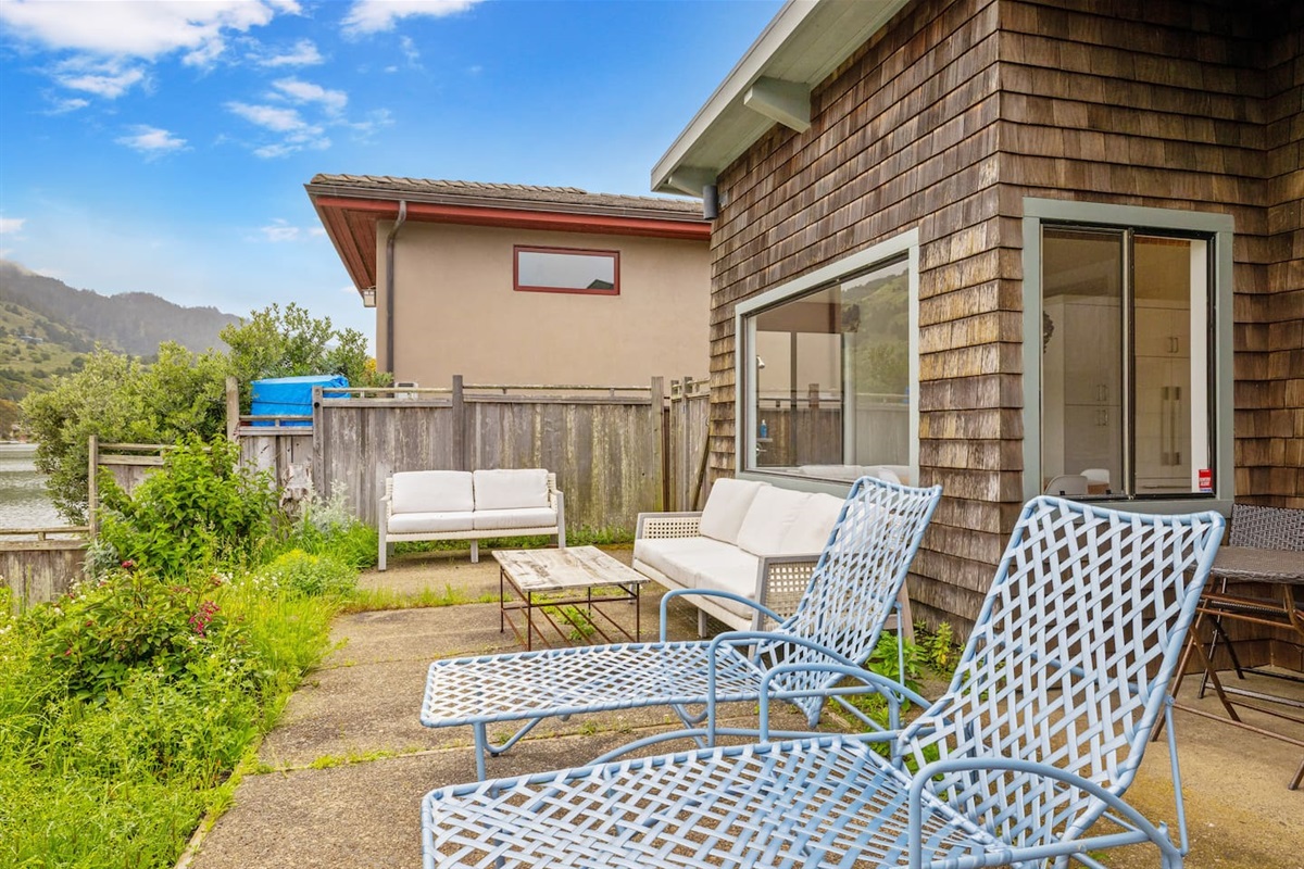 Outdoor lounge chairs on a private patio by the water.

