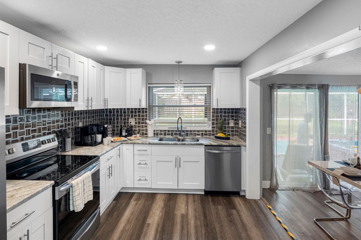 This fully equipped kitchen features modern stainless steel appliances, spacious countertops, and a sleek tile backsplash—perfect for preparing anything from a morning coffee to a gourmet meal.