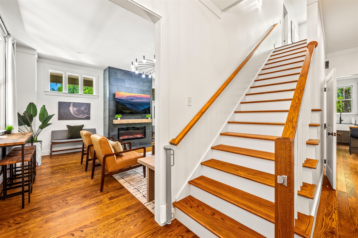 Step into style—this modern entryway opens to the spacious main living room and features a wide staircase leading to the second floor. A sleek baby gate is installed for safety without sacrificing aesthetics.