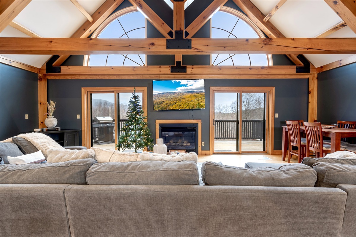 Unwind together in the vaulted living room where soaring beams, cozy seating, and a fireplace set the tone for unforgettable nights.