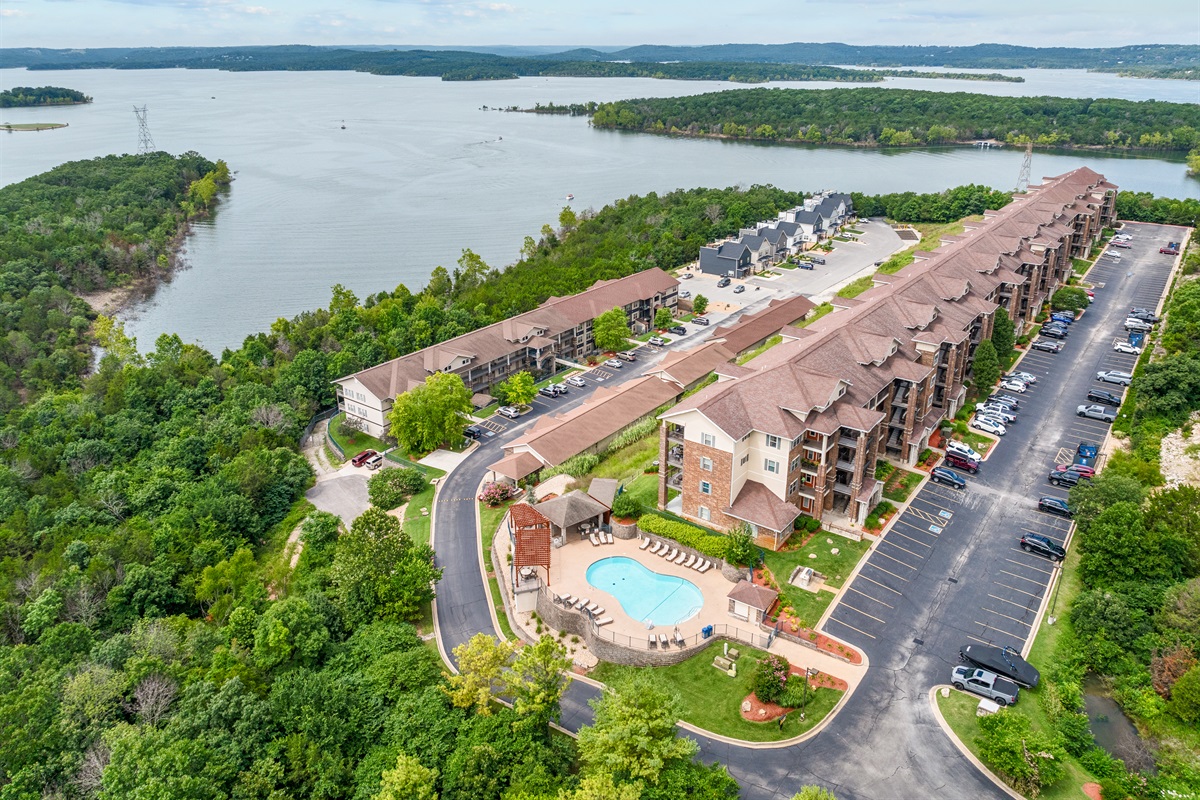 A dramatic aerial of the lakeside grounds and the building’s elevated setting above the water.