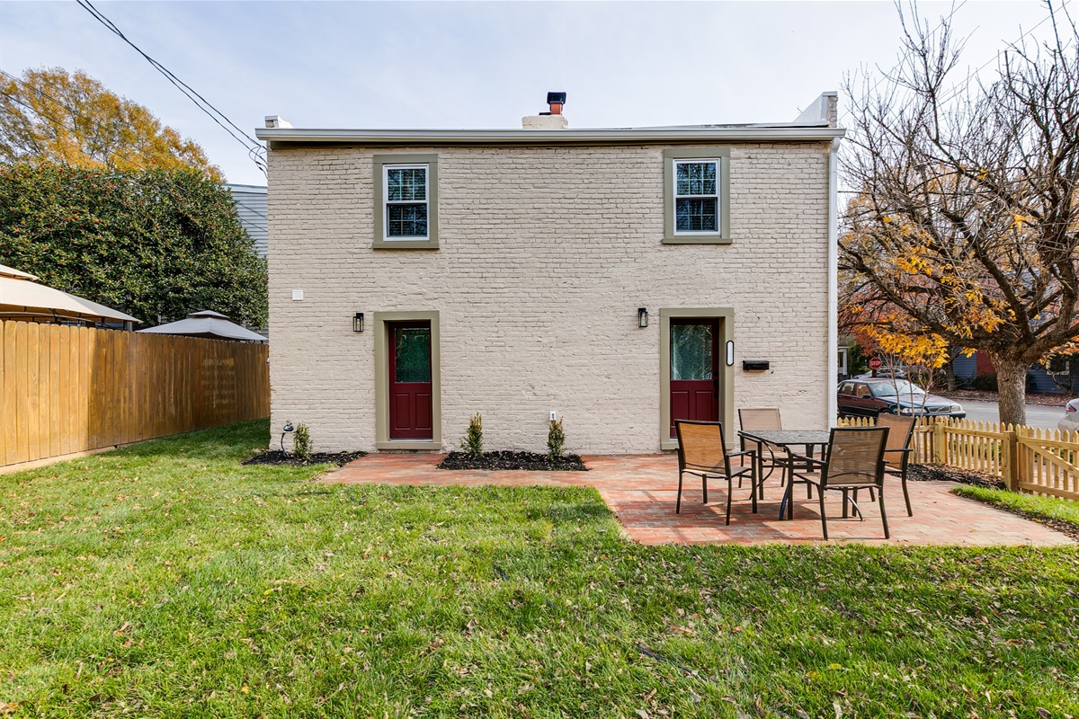 Charming Exterior: Relax on the patio surrounded by lush greenery and inviting brick pathways!