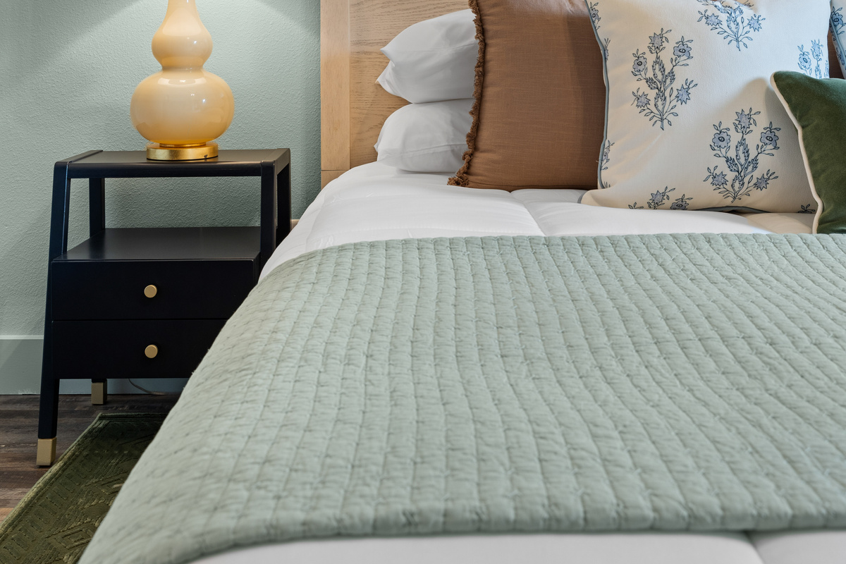 Unwind in the Bluebonnet Room beneath a spindle headboard and soft watercolor art.