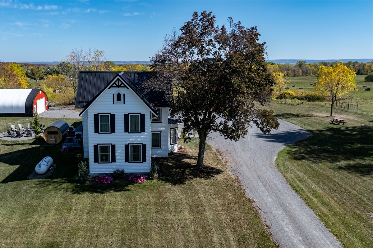 Inviting country driveway leading to a peaceful getaway surrounded by open fields and tall trees