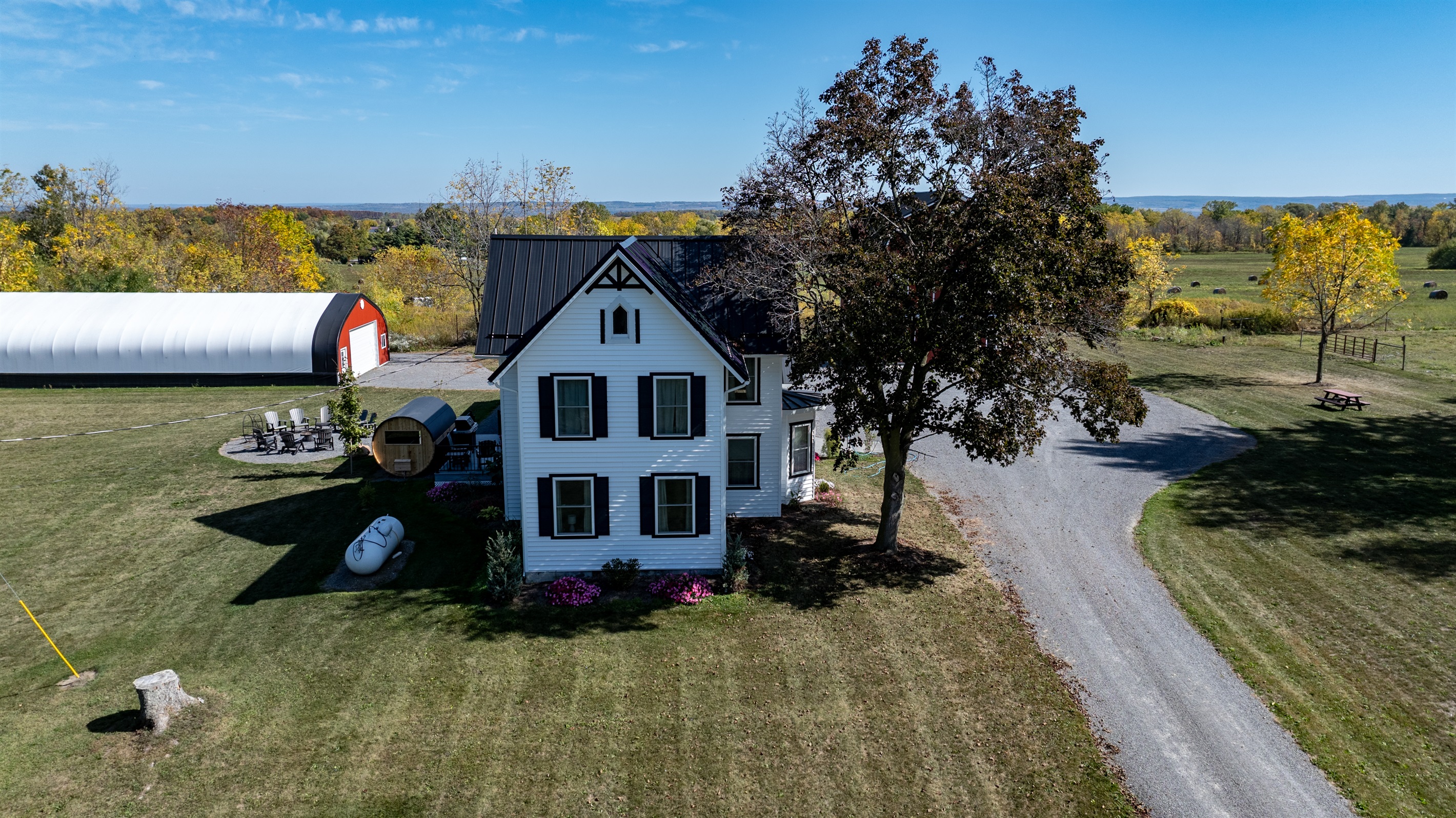 Inviting country driveway leading to a peaceful getaway surrounded by open fields and tall trees