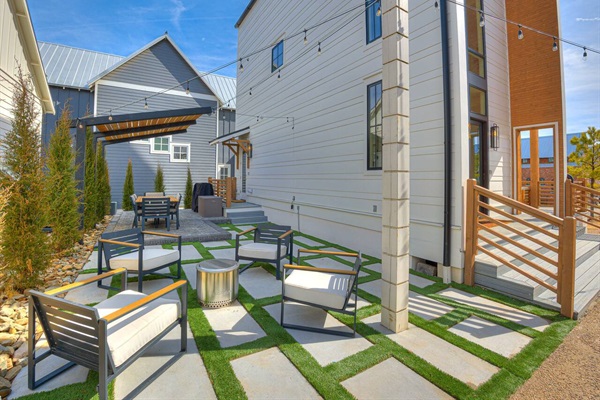 Back patio area with string lights, fire pit, and dining table for outdoor fun