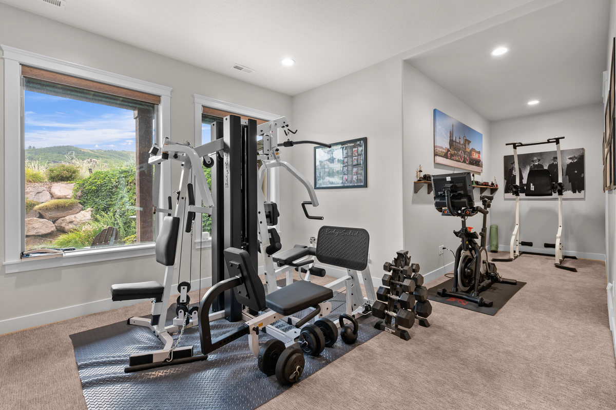 Private fitness room with a multi-station gym, free weights, and stationary bike overlooking scenic mountain views.