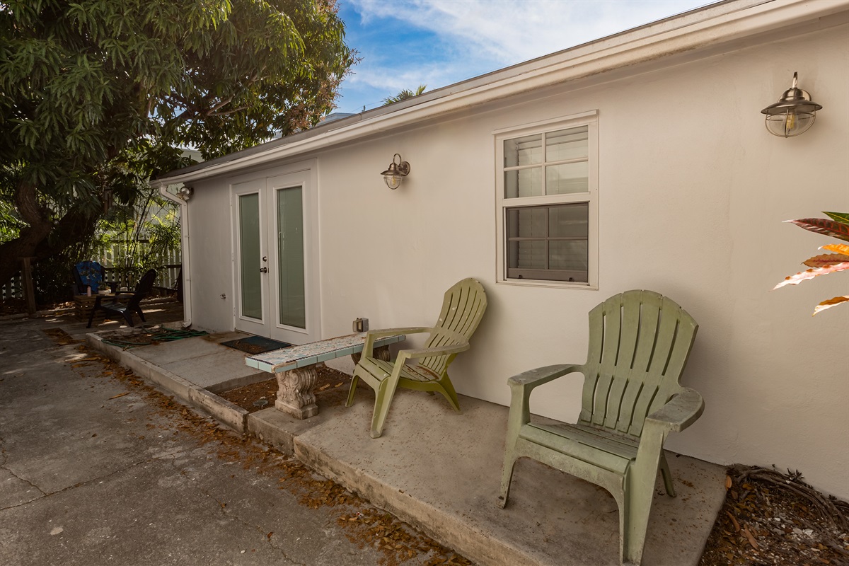 Patio Oasis: Unwind in classic Adirondack chairs beneath vibrant greenery and sunny skies!