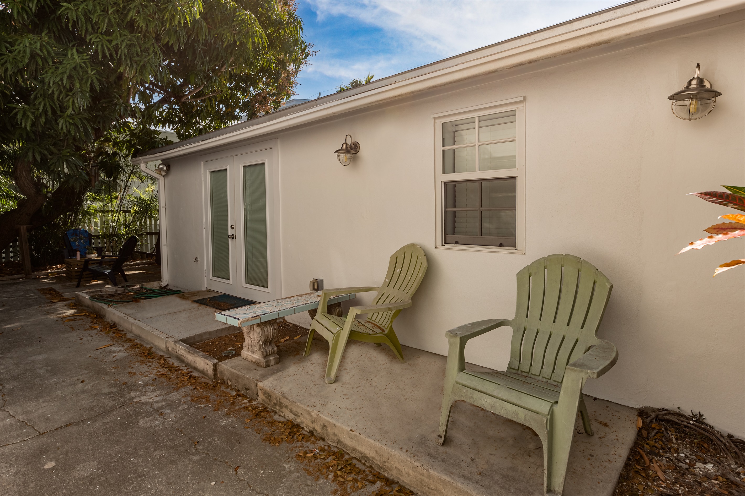 Patio Oasis: Unwind in classic Adirondack chairs beneath vibrant greenery and sunny skies!