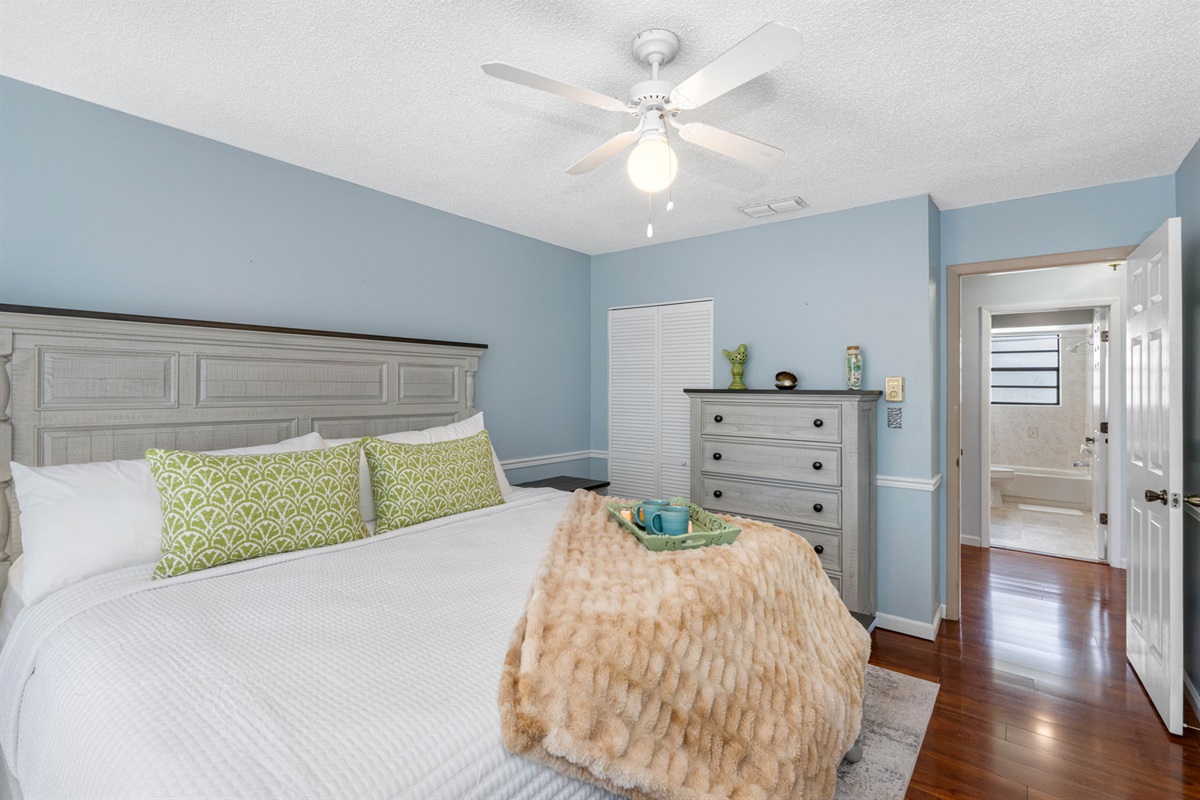 With its coastal-inspired tones, plush bedding, and fresh green accents, this bedroom is a soothing escape just steps from the bath.