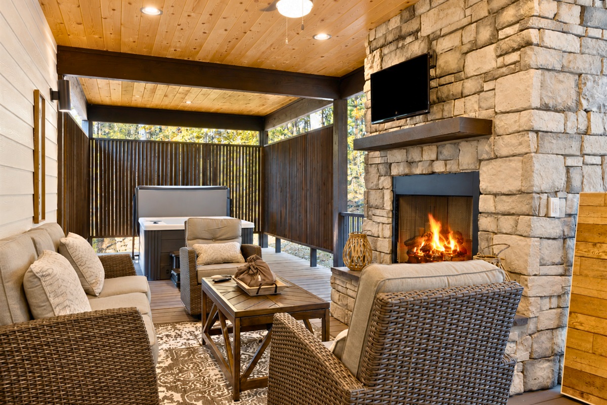 The outdoor living area features cozy seating, a gas fireplace, and a relaxing atmosphere perfect for enjoying every season in comfort.