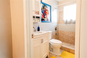 Chic Bathroom Retreat: Complete with Toilet, Sink, and Stylish Cabinet Mirror, Accentuated by a Striking Painting of a Woman with a Blue Frame 🚽🚰🖼️