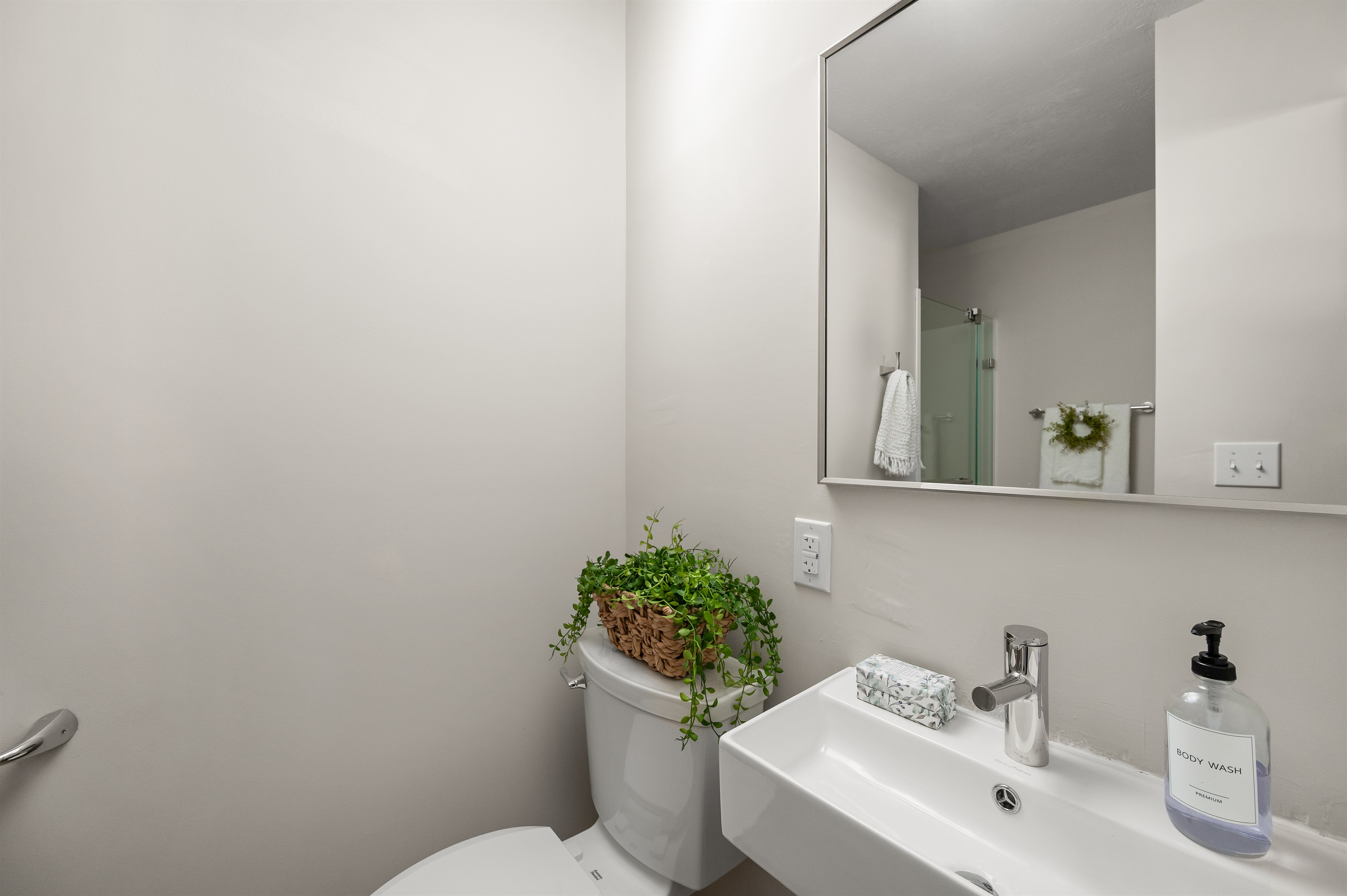 Full bathroom includes a toilet, sink, and spacious walk in shower with newly updated modern finishes.