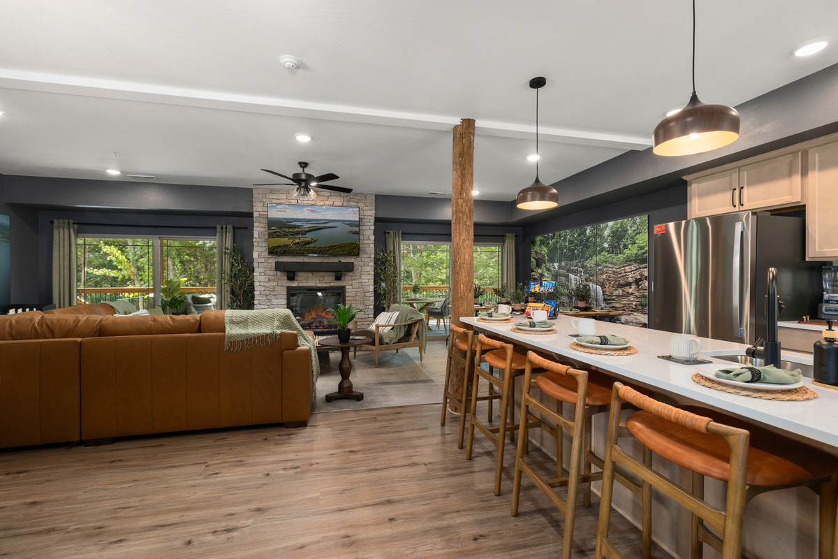 Open-concept great room where the island kitchen, dining, and stone fireplace all share the view.