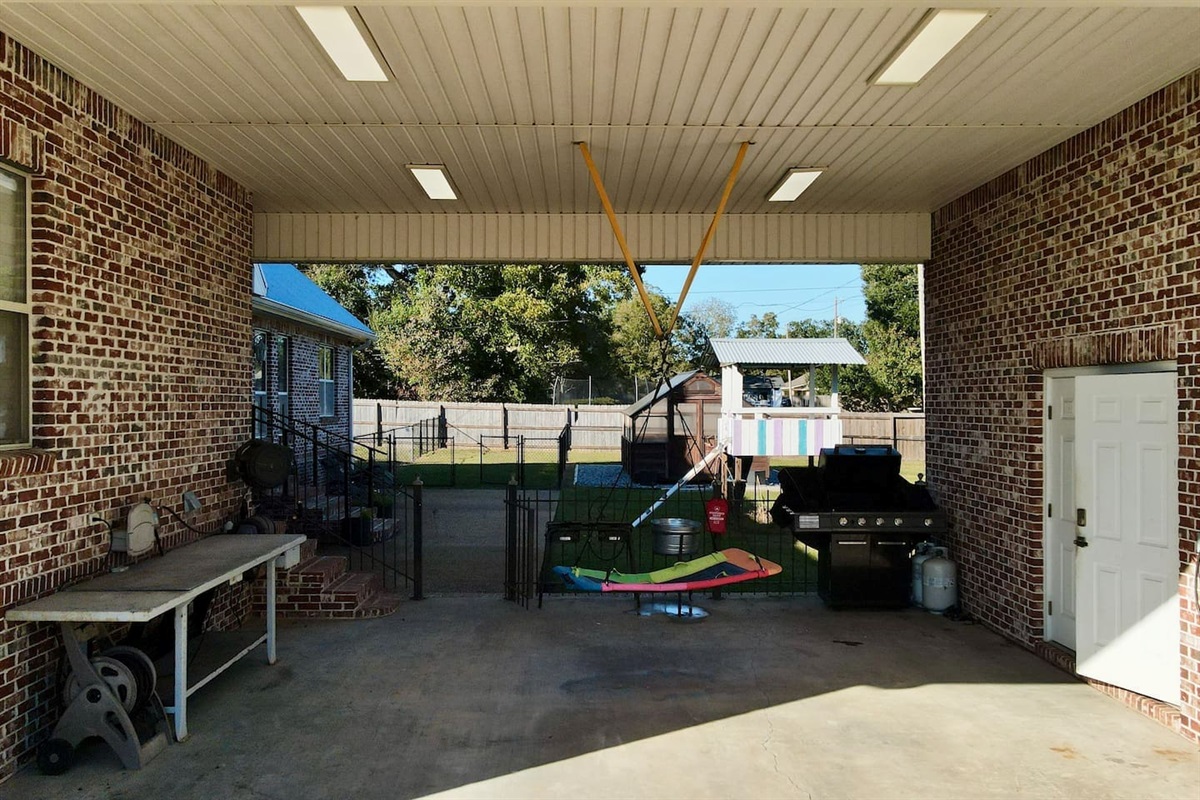 Green bins, a workbench with tools, and a propane grill make the space functional for both recreation and daily use.