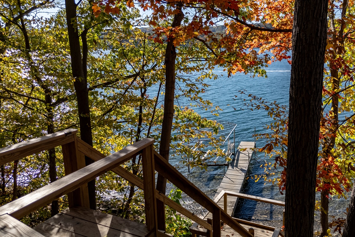 Tree-lined stairs leading to sand/stone beach and lakeside seating.