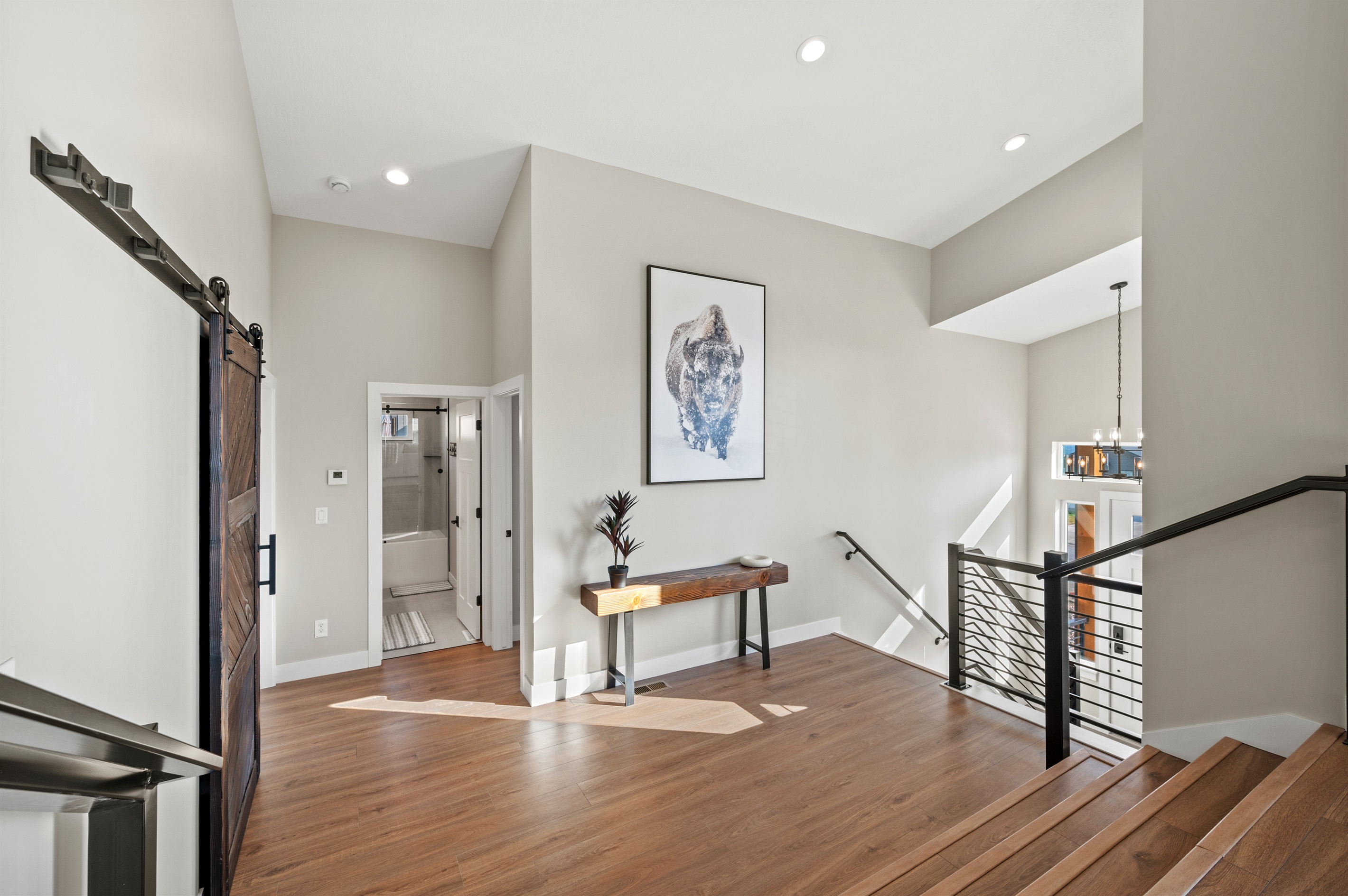 Landing area featuring a bison accent and bench, with steps leading up from the entryway and more steps to the upper level, all illuminated by recessed lighting.