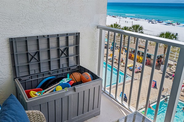 Toy chest filled with beach and pool toys, pickleball paddles, tennis rackets, floats, sports equipment, and more 