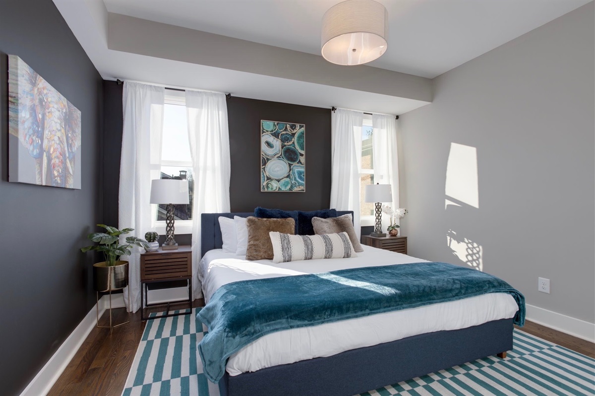 - Rest easy in this serene space with plush pillows, rich textures & calming colors - Natural light pours in from both sides, creating a bright, peaceful retreat - From the striped rug to the bold feature wall, every detail is designed to soothe & inspire