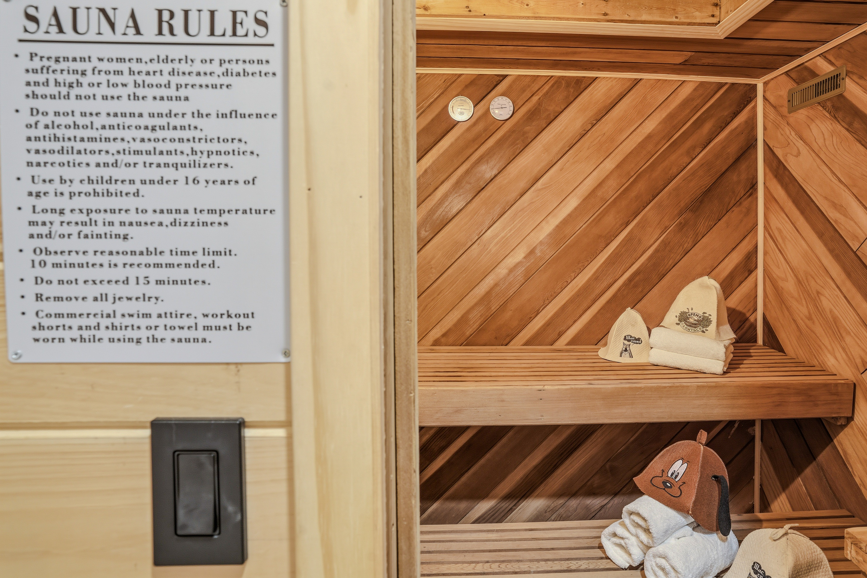 Indoor sauna interior — cedar walls, built-in benches, and house rules posted at eye level