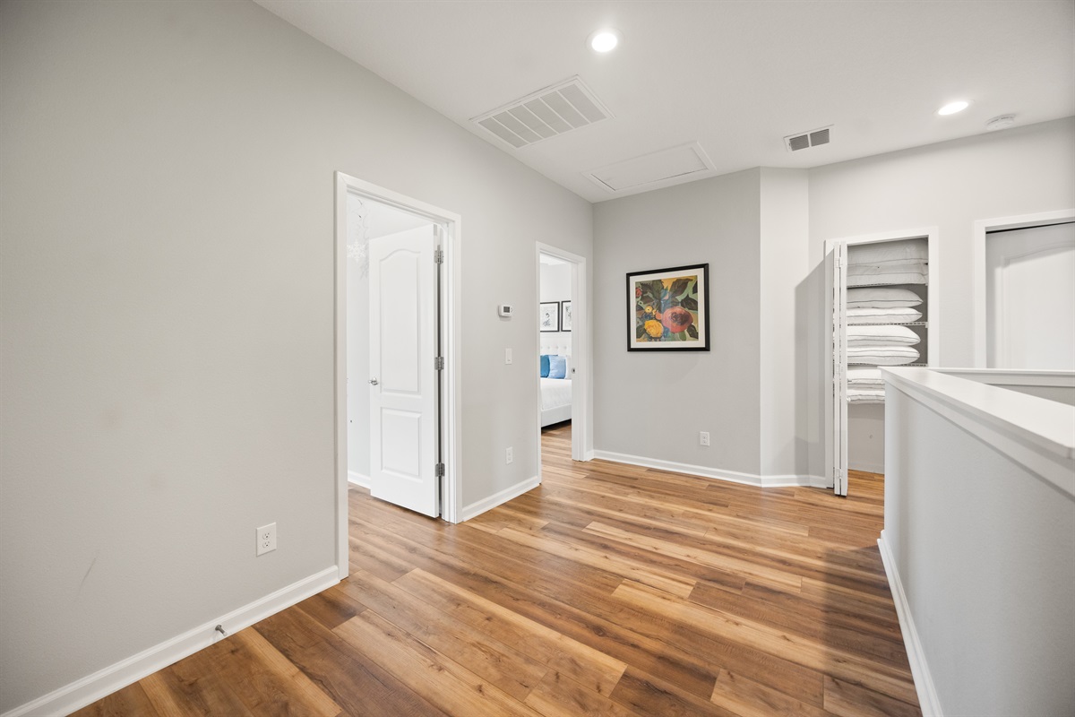 The hallway at the second floor, with access to four of the bedrooms and the pillow closet