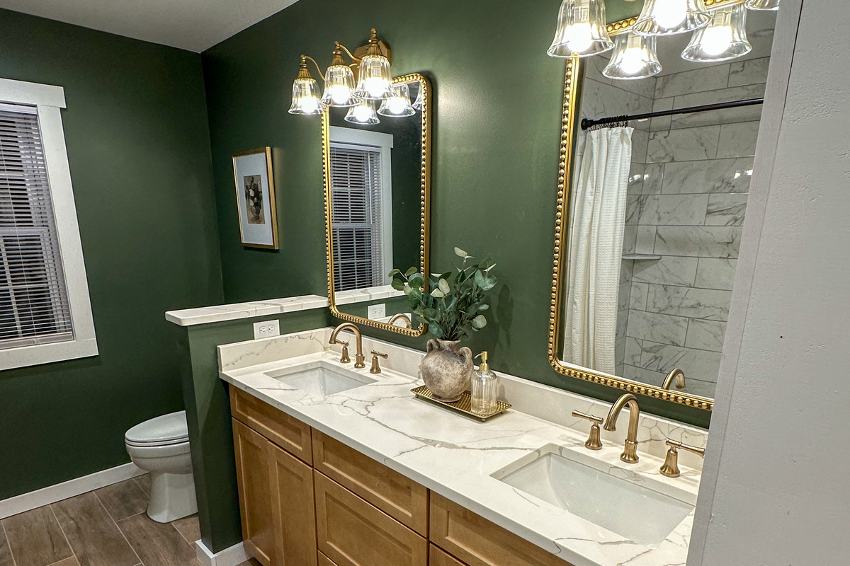 Spa inspired downstairs bath featuring a double vanity, custom tile shower, warm brass finishes, and rich green walls. Thoughtfully designed with both style and function in mind for families and groups. 
