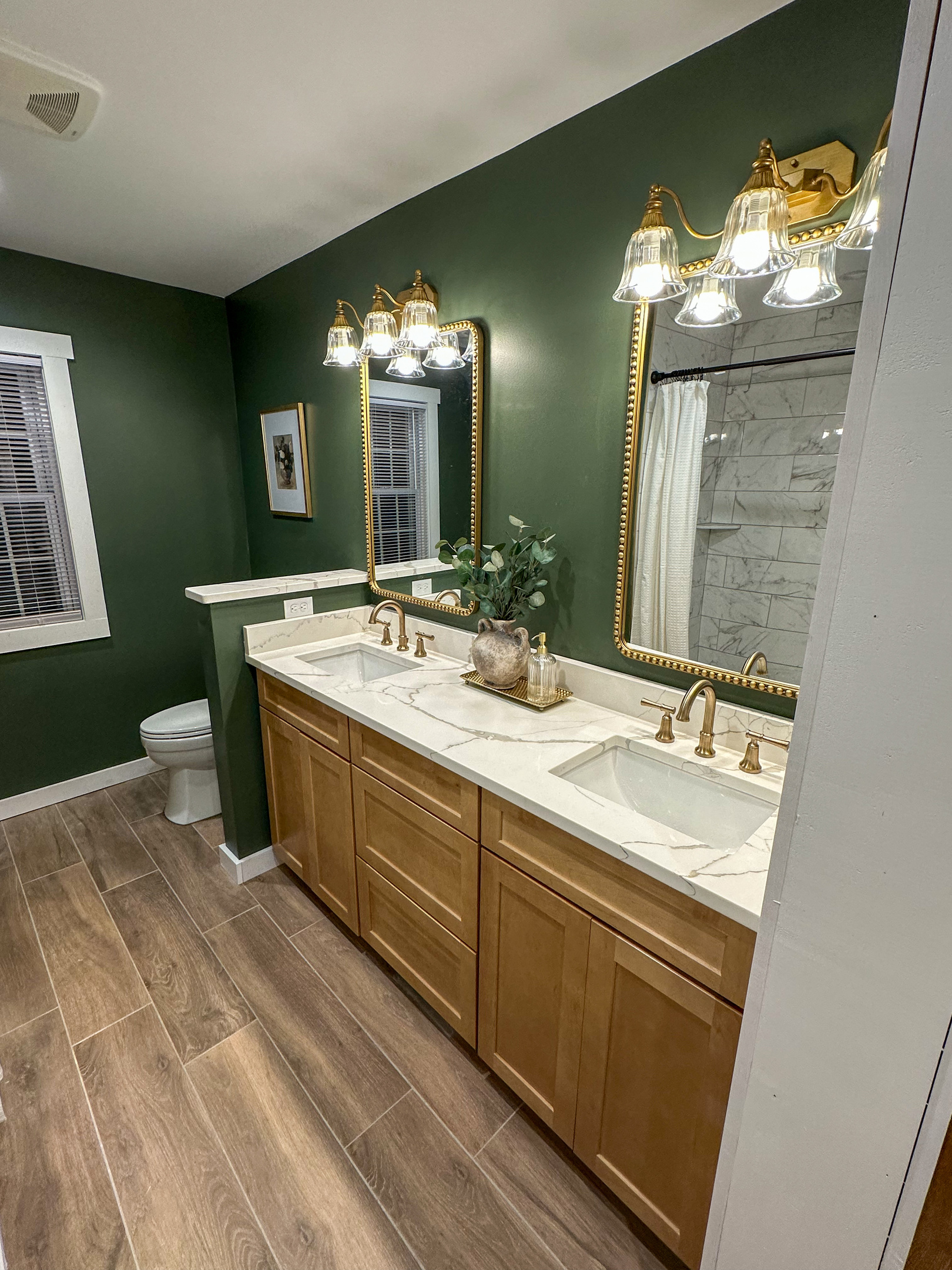 Spa inspired downstairs bath featuring a double vanity, custom tile shower, warm brass finishes, and rich green walls. Thoughtfully designed with both style and function in mind for families and groups. 
