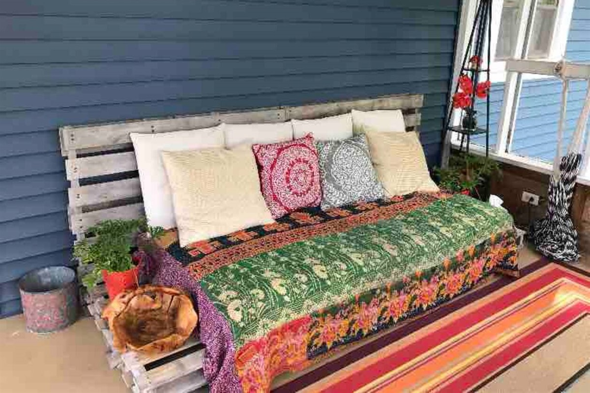 Bohemian style screened in porch with twin bed/couch, dining table, and hammock. Great for lounging during warm weather!