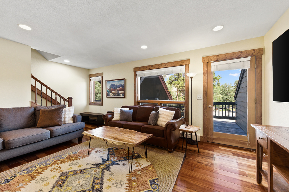 Living room with balcony that features dining, seating and view of woods and neighborhood. 