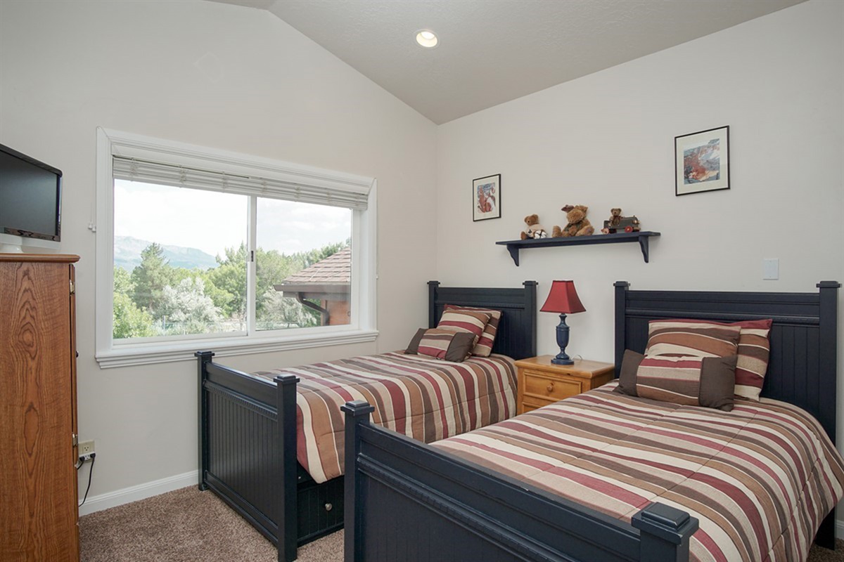 A thoughtfully designed mountain view bedroom, with two twin beds— perfect for kids, friends, or additional guests.