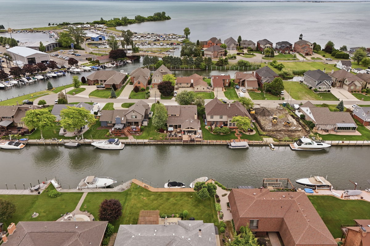 Aerial waterfront view of a quiet canal neighborhood with private docks, boats, and well-maintained homes along the shoreline. Scenic and peaceful setting offering true lakefront living and easy water access.