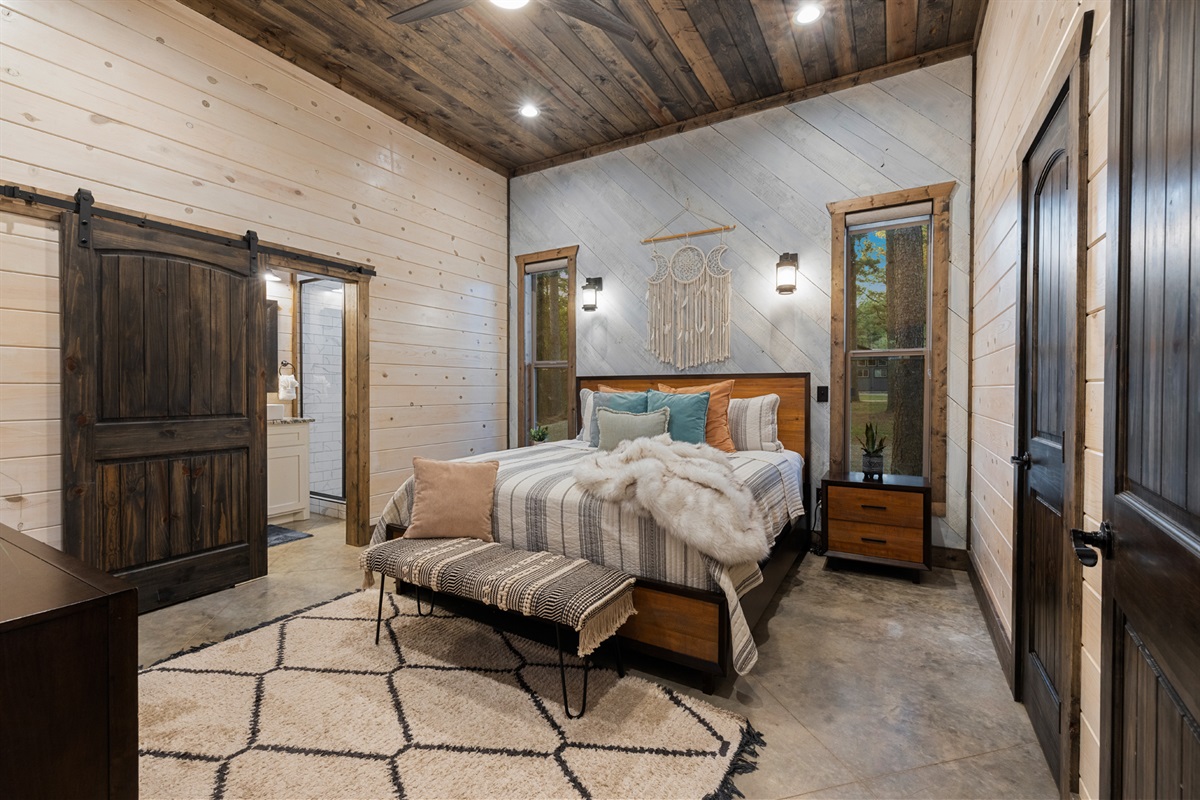 Soft bedding, warm wood accents, and gentle light set the tone for deep rest. Wake to calm forest views and a slow, unhurried morning in this King bedroom with attached bathroom.