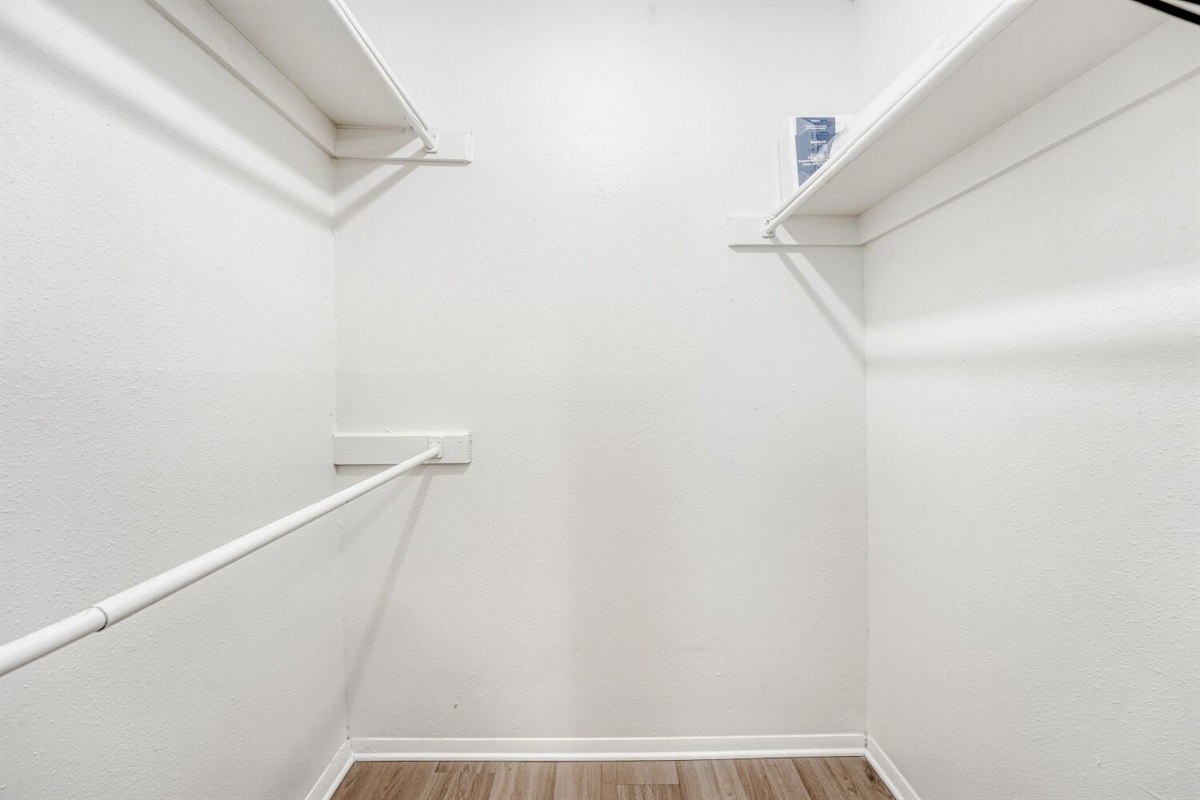 Spacious walk-in closet with built-in shelving and bright lighting.