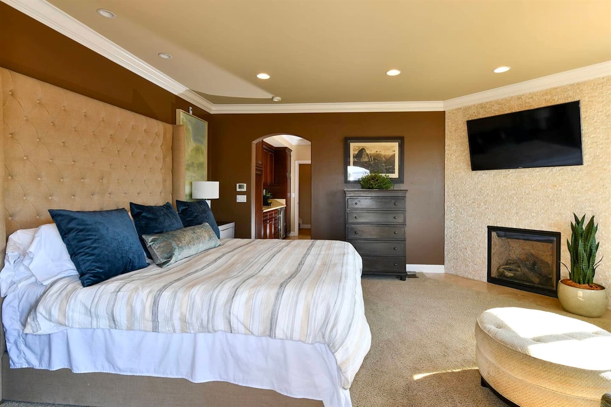 Primary bedroom with king bed, smart tv, andfireplace.